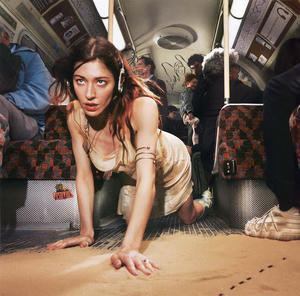 Caroline Polachek - Desire, I Want to Turn into You Cover art of Caroline Polachek's Desire, I Want to Turn into You.
It shows Caroline crawling on the floor of a subway car, into some sand.
Caroline is wearing headphones.
There are a number of people standing and sitting in the background, including a cameo by Danny L Harle, a frequent collaborator of Caroline's and this record's main producer.
