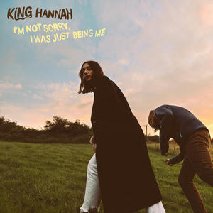 Cover art of King Hannah's I'm Not Sorry I Was Just Being Me.
It depicts the two band members walking in a field at sunset.
Hannah is looking back at the camera, while Craig appears to be falling over.