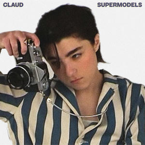 Cover art of Claud's Supermodels.
It shows Claud in a blue and white striped shirt.
They are looking through the lens of an old camera.